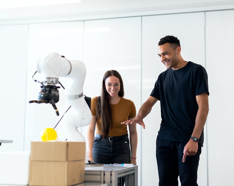two people testing a robotic arm for the manufacturing and supply chain facility